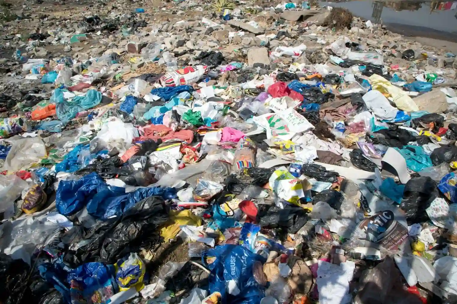 A vast landscape is covered in a dense layer of discarded plastic bags, food wrappers, and miscellaneous trash, creating a scene of significant environmental pollution