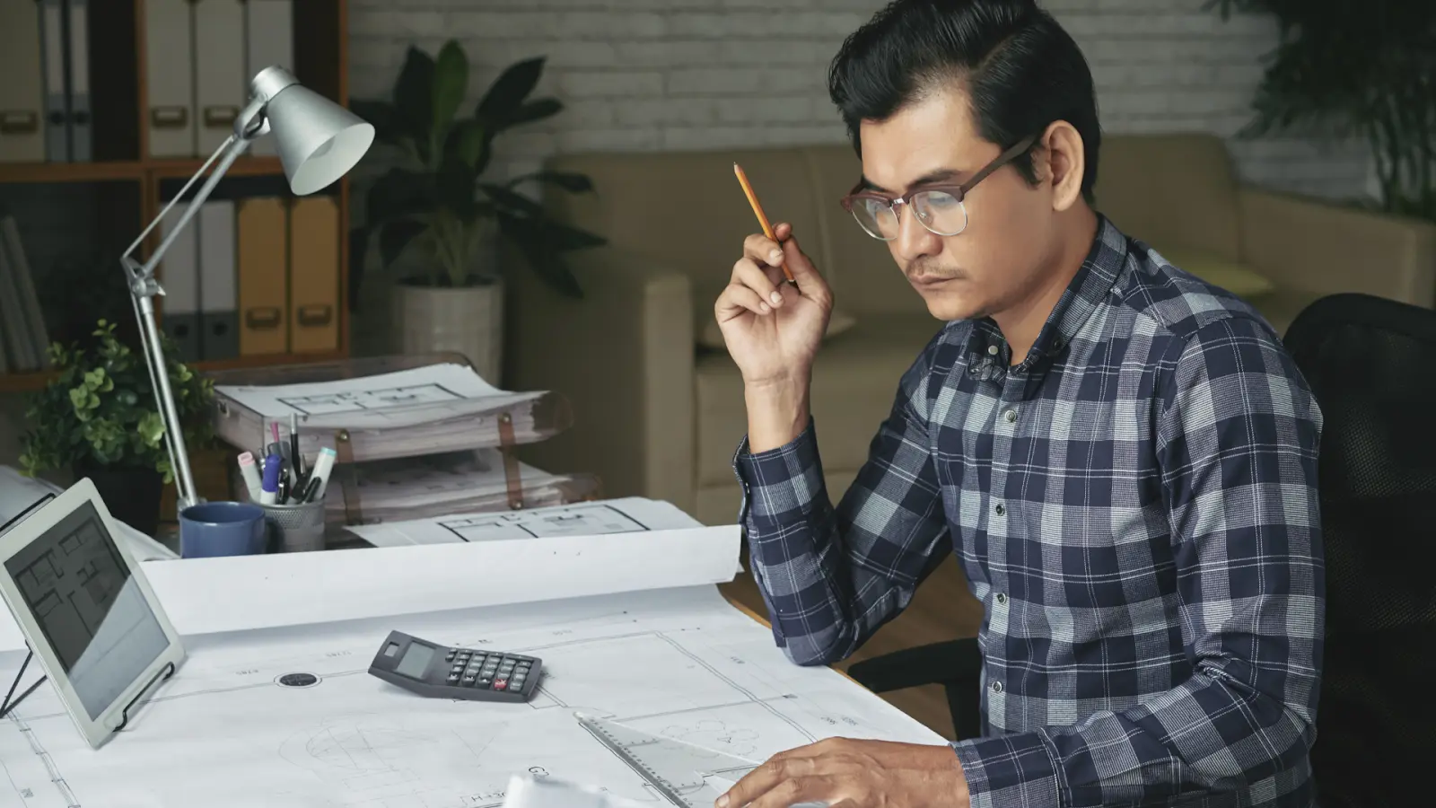 An analyst working with a calculator and blueprints to organize a Realized Trade Cost Taxonomy for reporting.