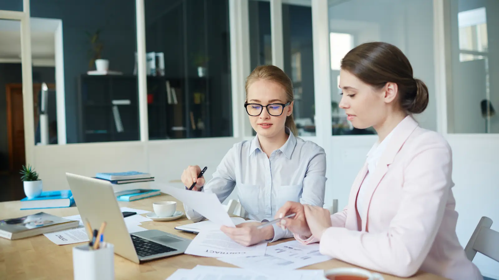 Two professionals reviewing documents and a laptop to apply Decision Rules that turn data into business actions.