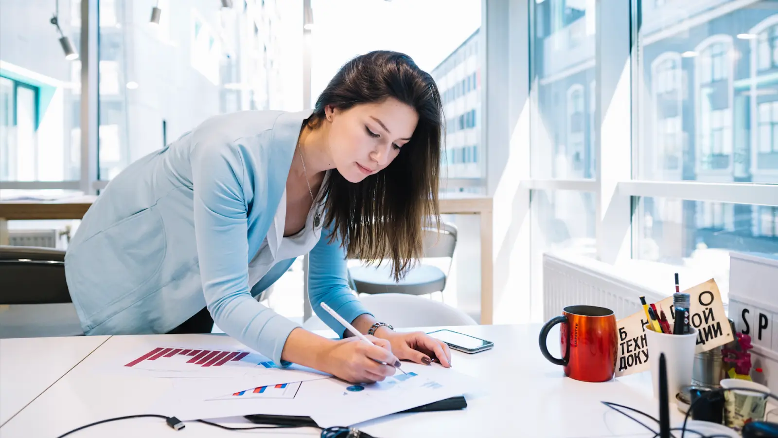 A woman leaning over a desk marking a chart to develop a strategic 90-Day Digitization Roadmap.