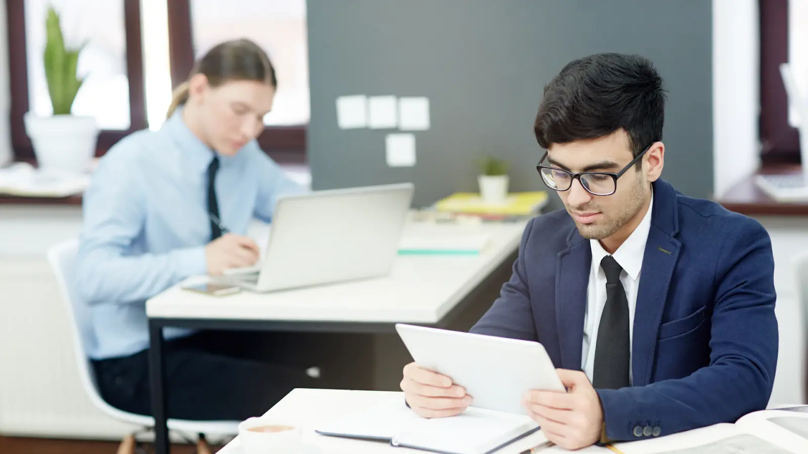Two colleagues using a tablet and laptop to demonstrate practical Examples of Digitization within a modern office.