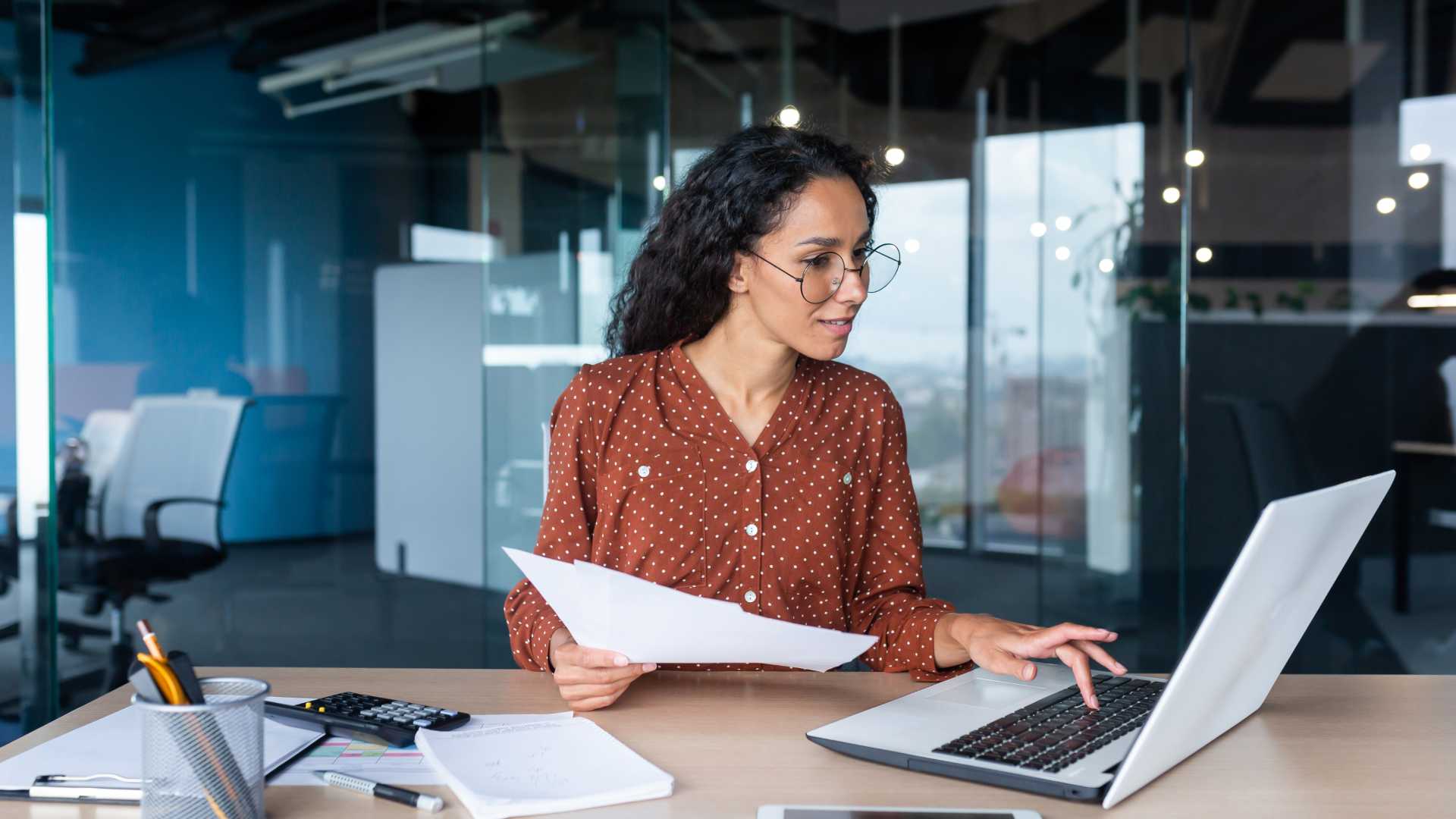 Professional reviewing documents and laptop while analyzing trade promotion effectiveness.