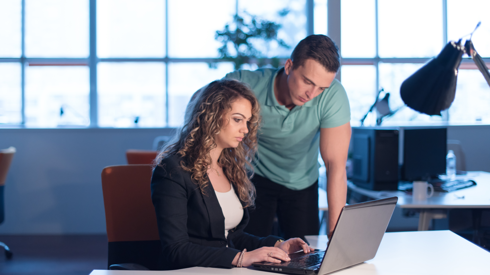 Two colleagues reviewing a laptop screen to compare distributor deductions with retailer chargebacks.