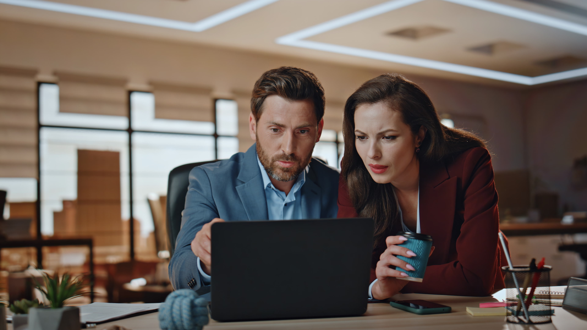 Two colleagues reviewing deduction data on a laptop to strengthen their CPG deduction process.