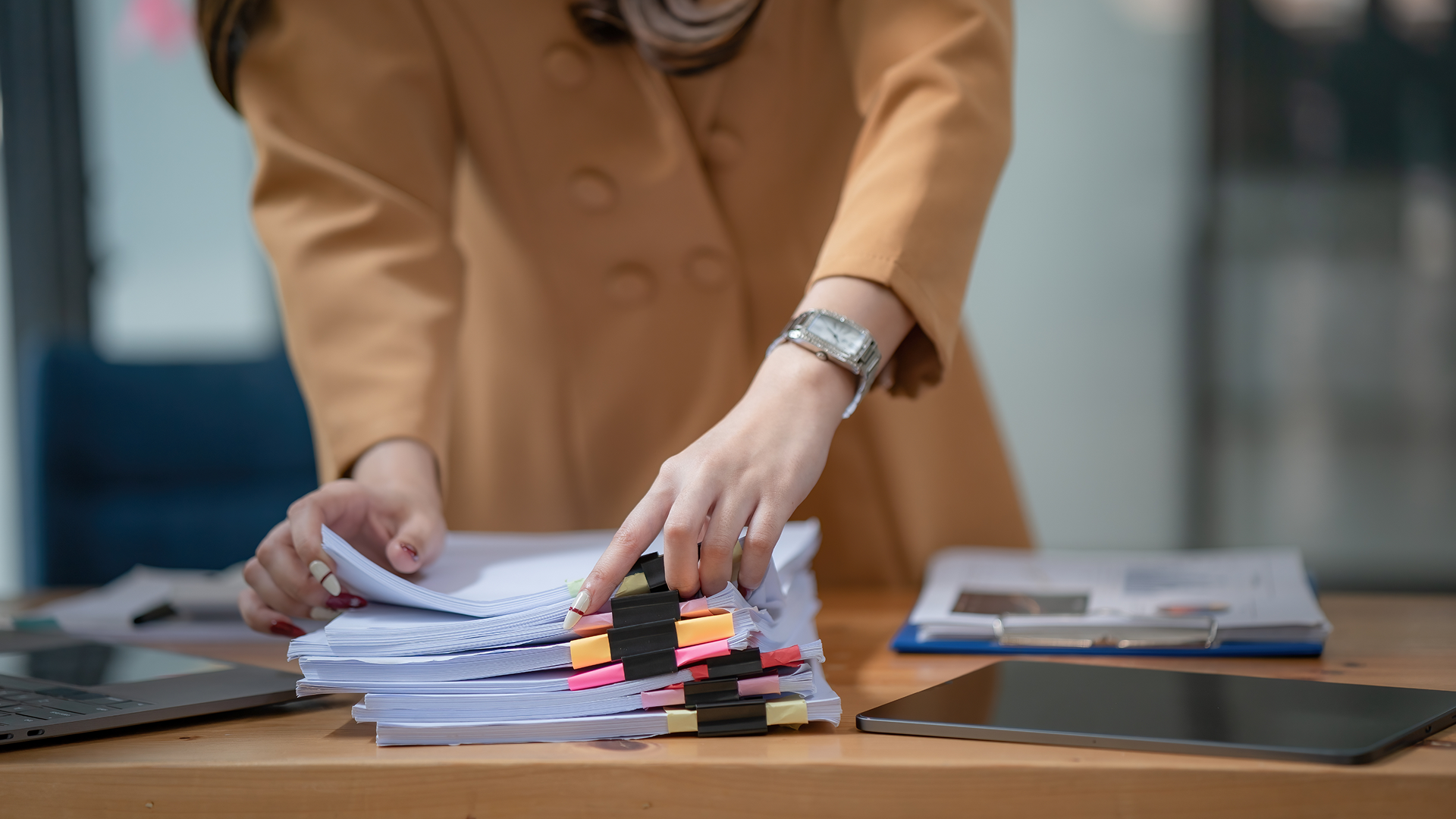 Close-up of a professional sorting tabbed paper documents, representing the UNFI deduction triage process.