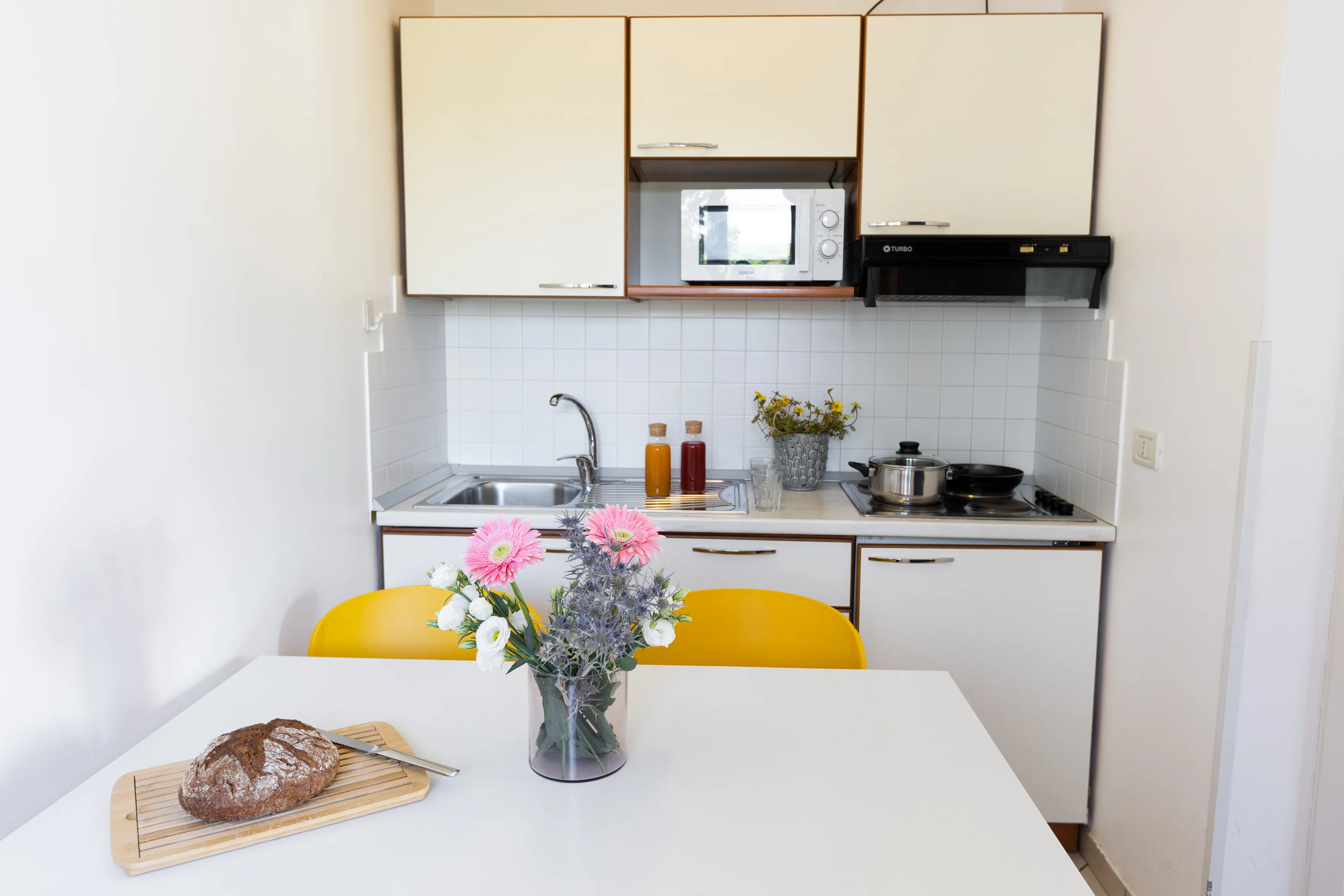 Reception con banco in legno curvo, porta di vetro sullo sfondo e sedie in legno con cuscini lungo la parete destra.