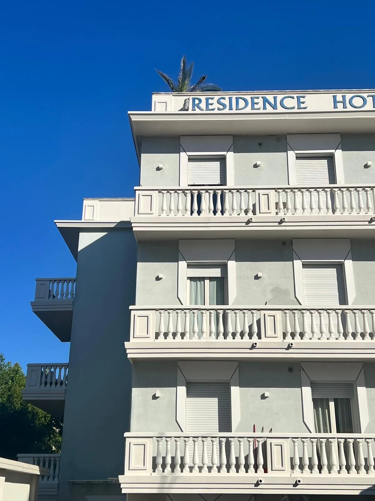 Facciata di un hotel residenziale bianco su cielo azzurro con balconi.