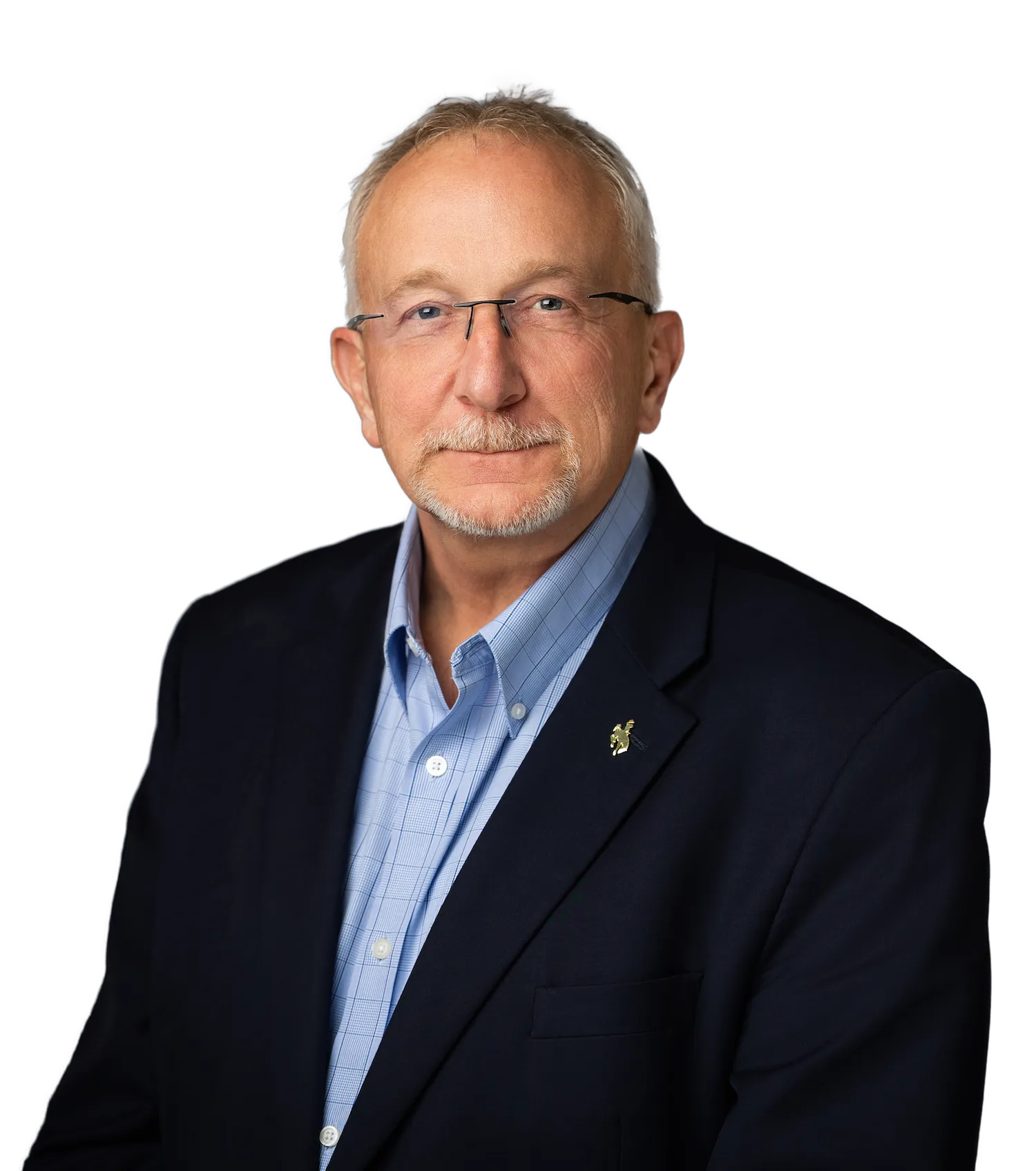 Portrait of a mature man with glasses, a light beard, wearing a blue checked shirt and a dark blazer with a lapel pin.