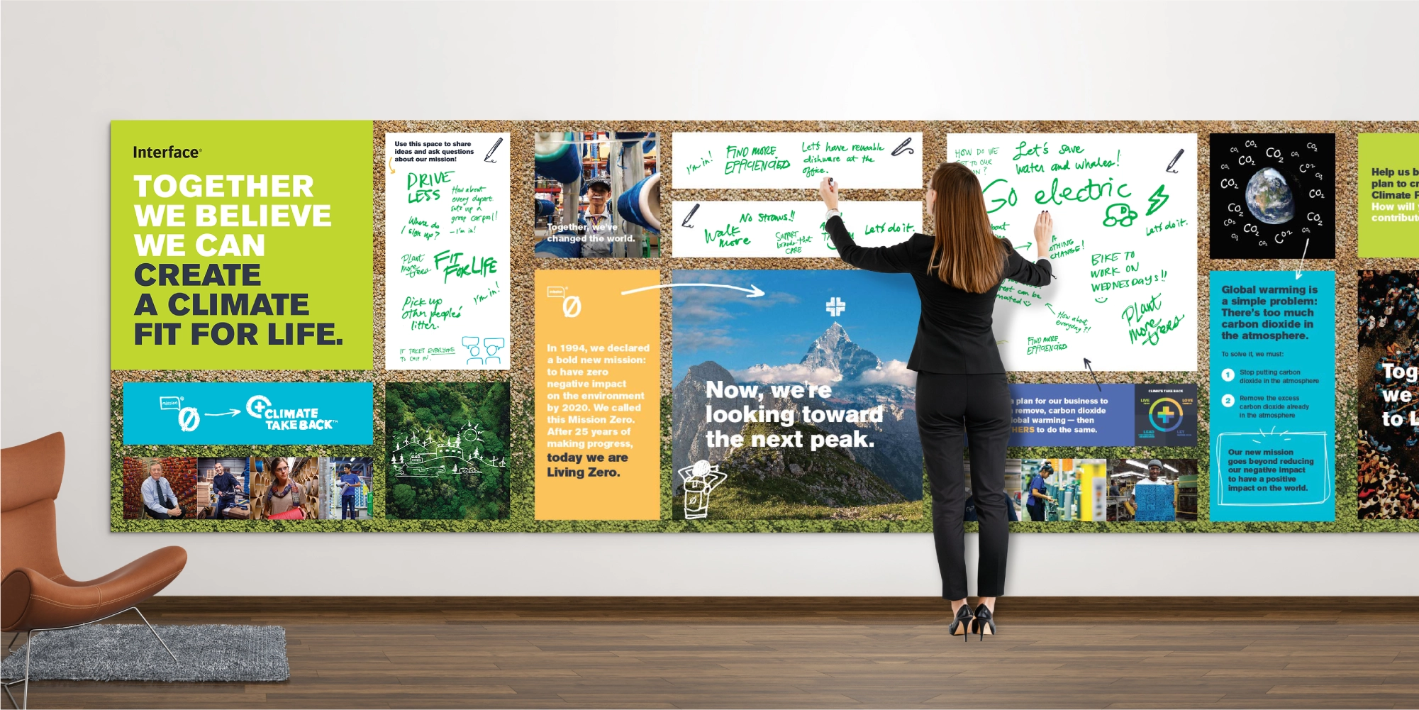 Woman writing green text on a large interactive climate change-themed wall display with messages and photos about environmental impact, mission zero, and saving the planet.