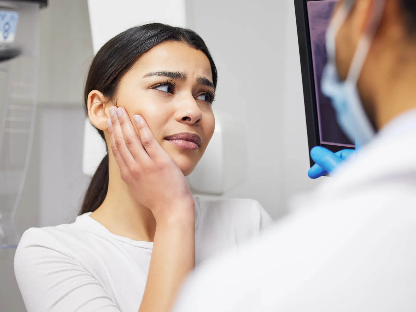 A woman looking at her face in the mirror.