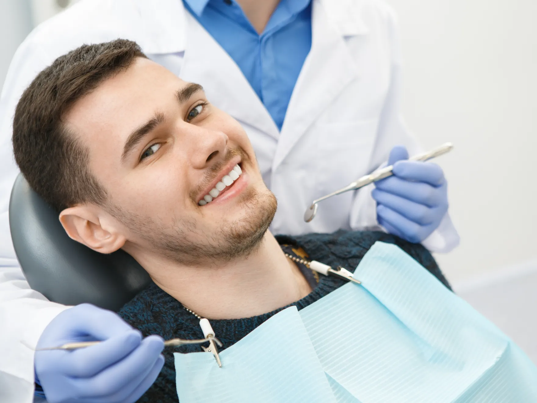 A man getting his teeth checked by a dentist.