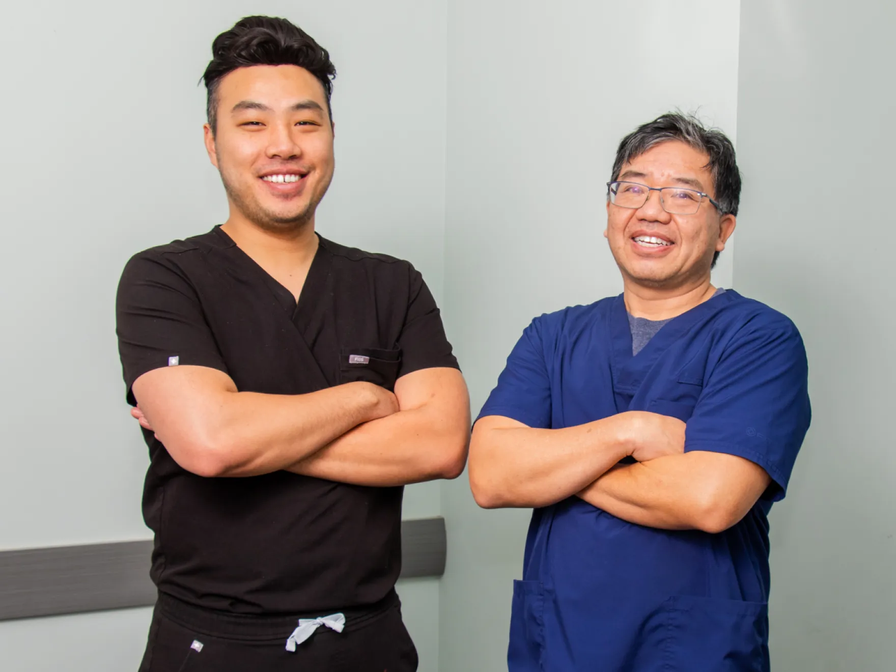 Two men in scrubs standing next to each other.