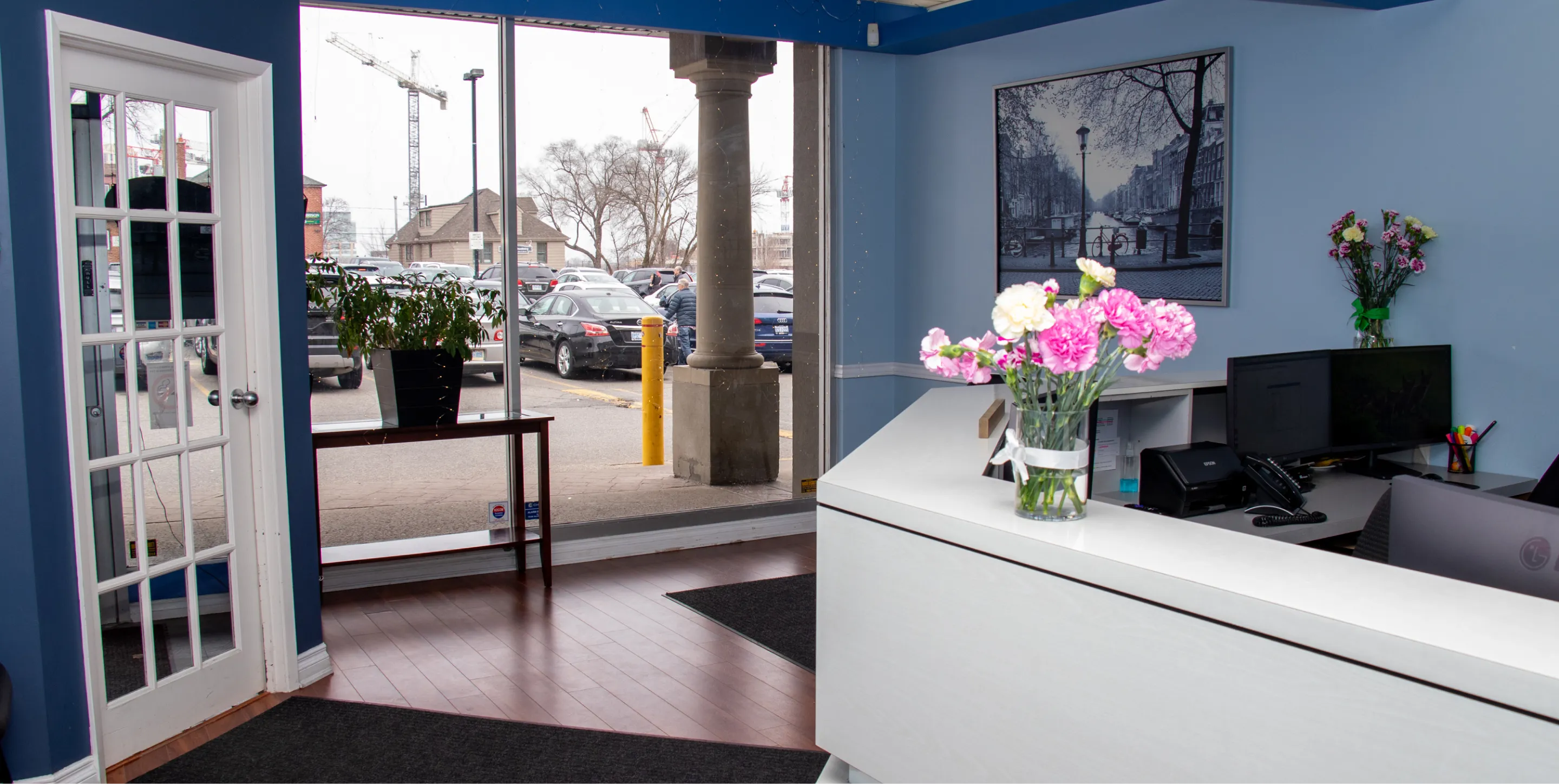A receptionist desk with a vase of pink and white flowers in a bright office lobby.