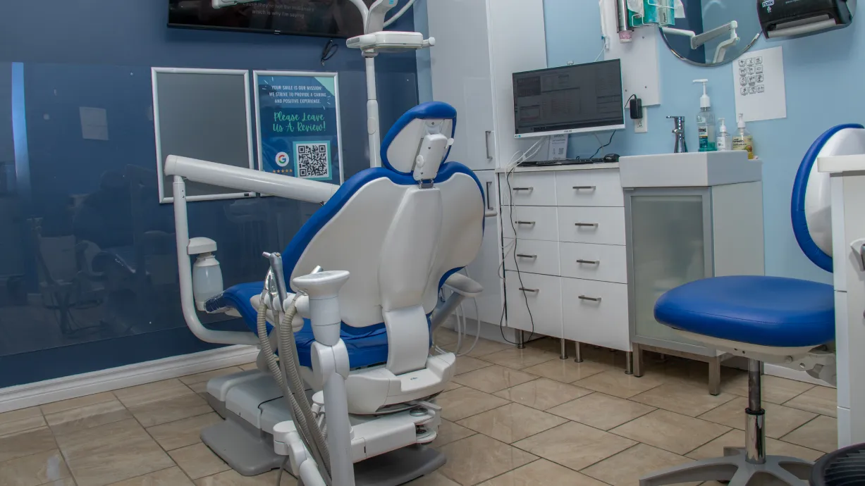 Dental office with a blue and white dentist chair, equipment, and a computer workstation.