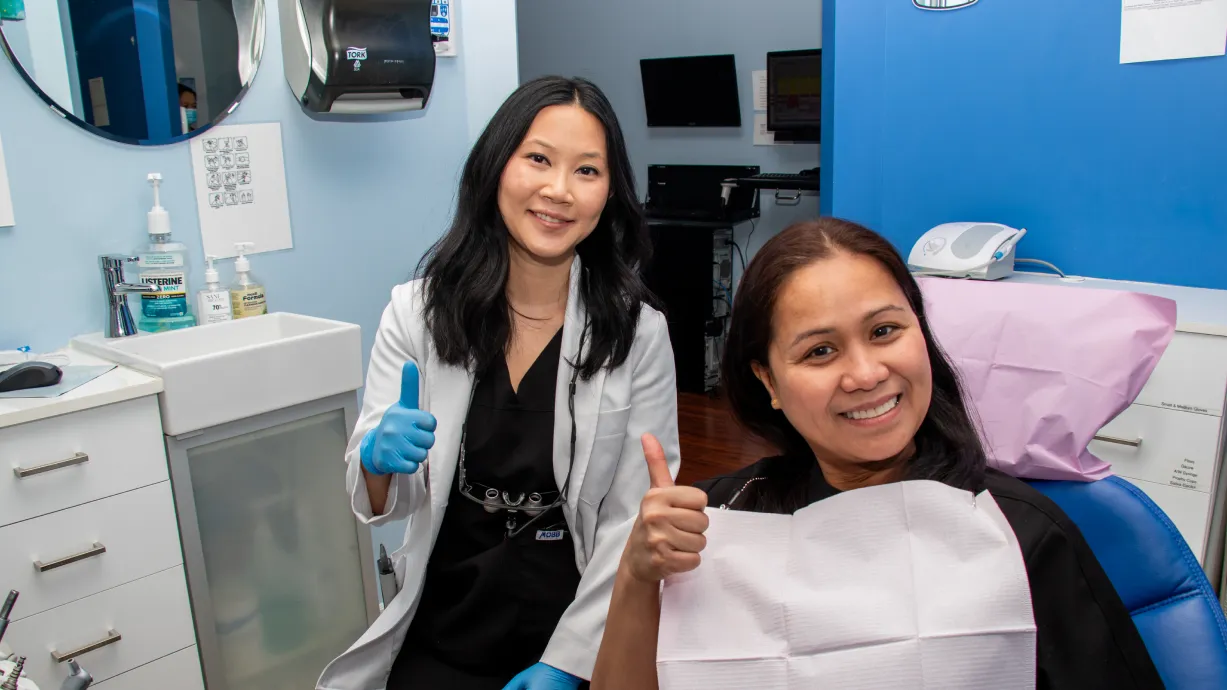 A woman smiling and talking on the phone at her desk.