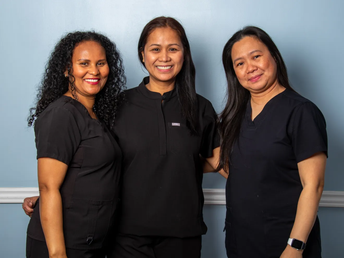 Two women smiling and posing against a light blue background.