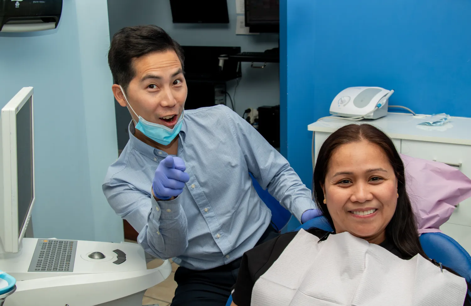Dentist and patient smiling in a dental clinic, both giving a thumbs-up gesture.