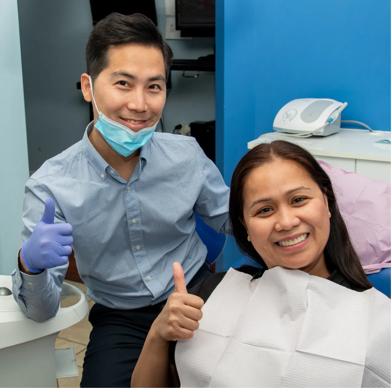Dentist and patient smiling and giving a thumbs up in a dental office.