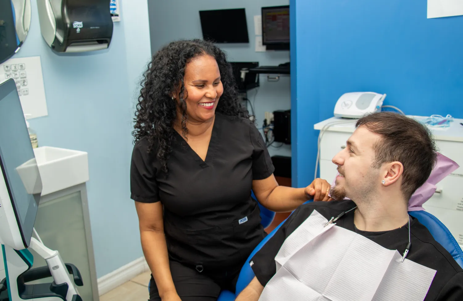 A person smiling while holding a dental model and a dental tool.
