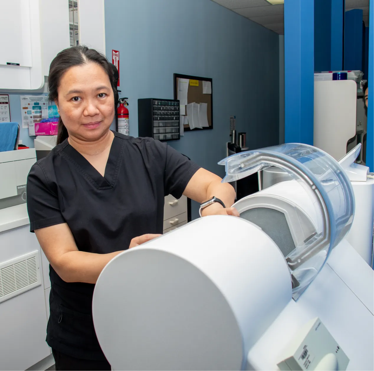 Two women smiling in a dental office, one in a lab coat, both giving thumbs up.