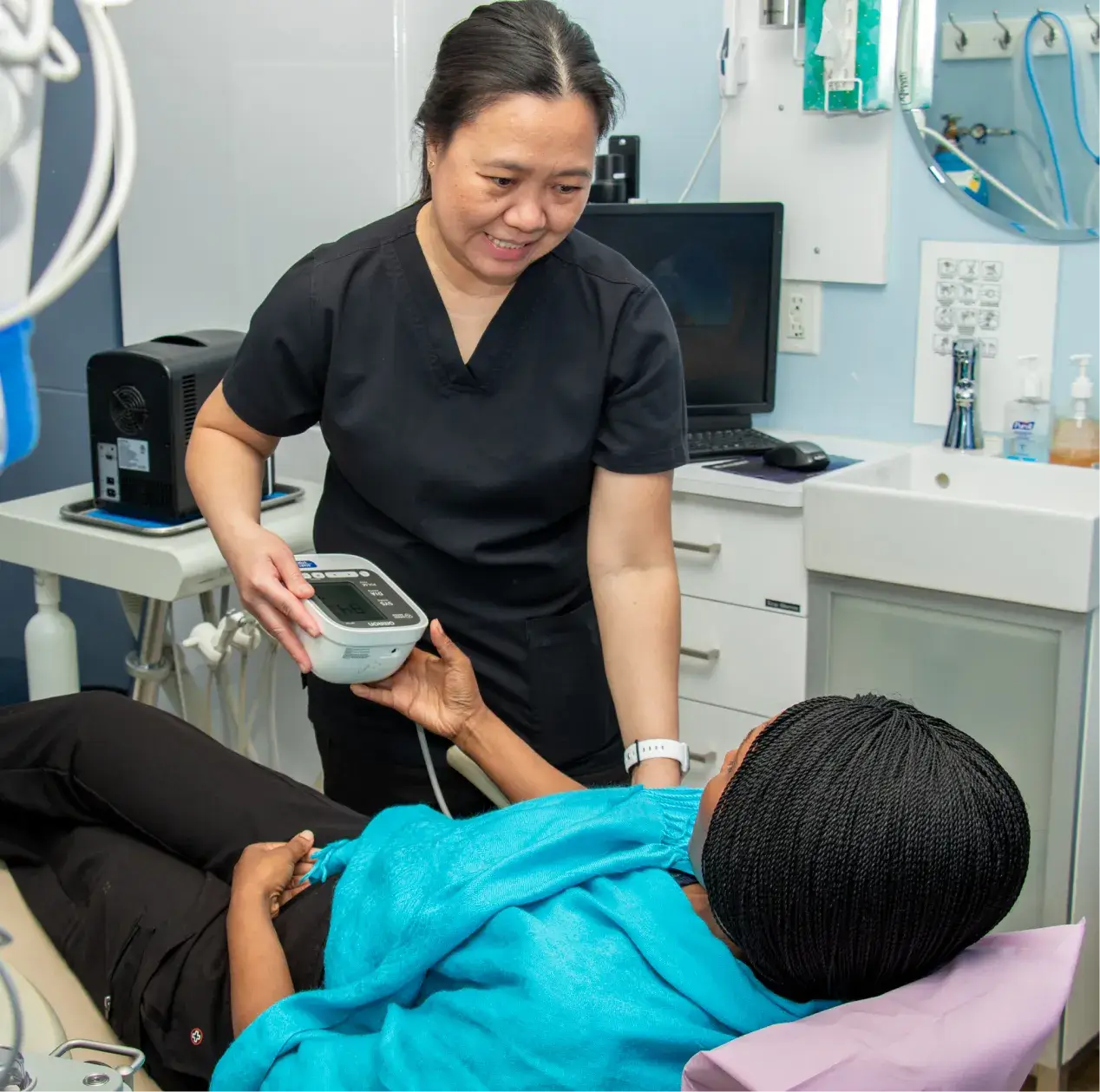 A healthcare worker takes a patient's blood pressure in a medical examination room.