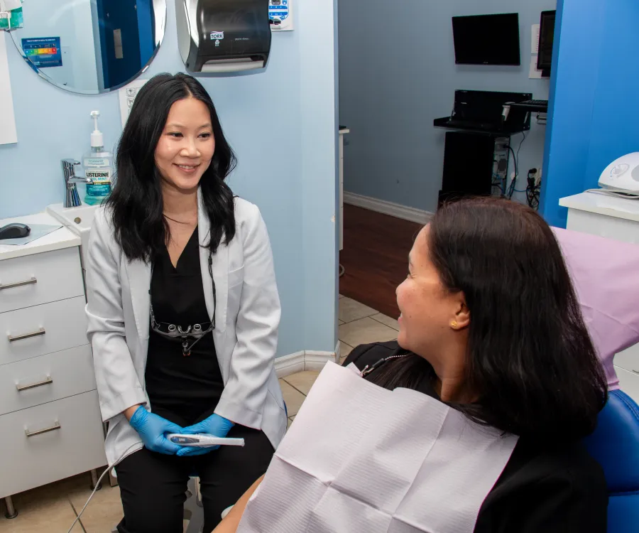 Dentist smiling and talking with a patient sitting in a dental chair.