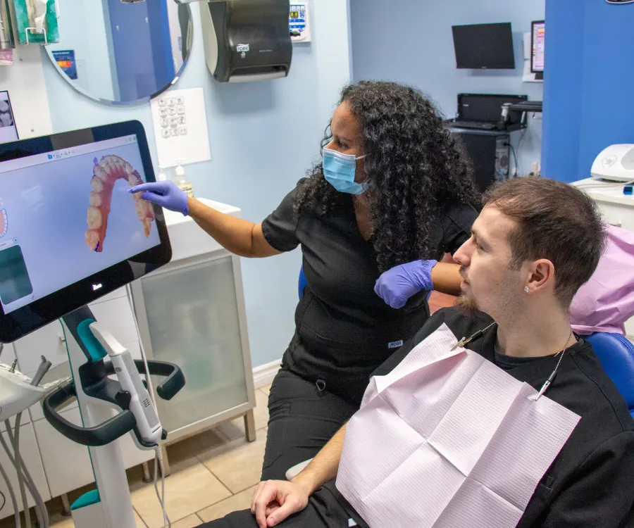 A dental professional shows a patient a digital model of teeth on a screen.