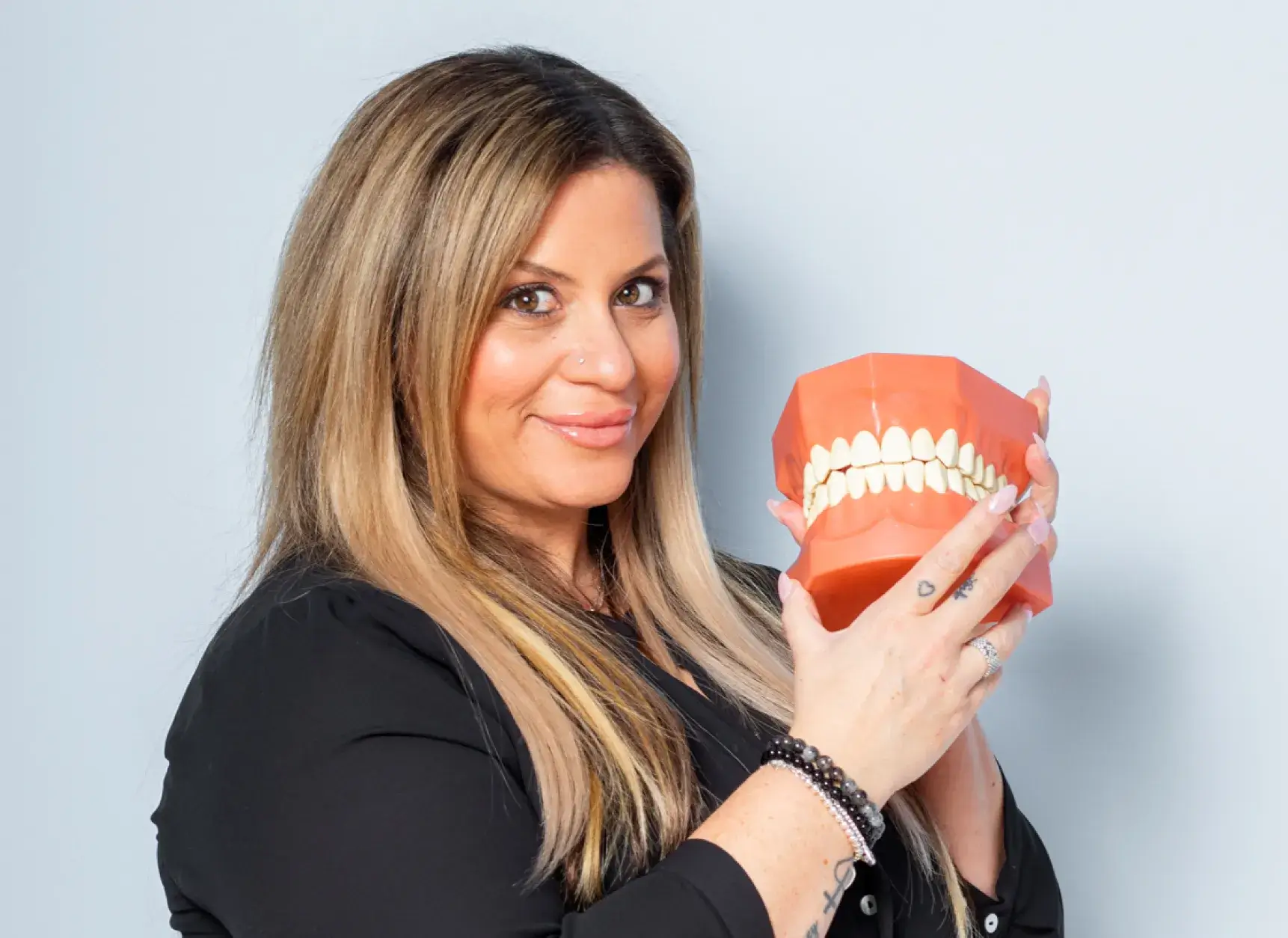 Family Dental Care of Tottenham team member smiling and holding a denture.