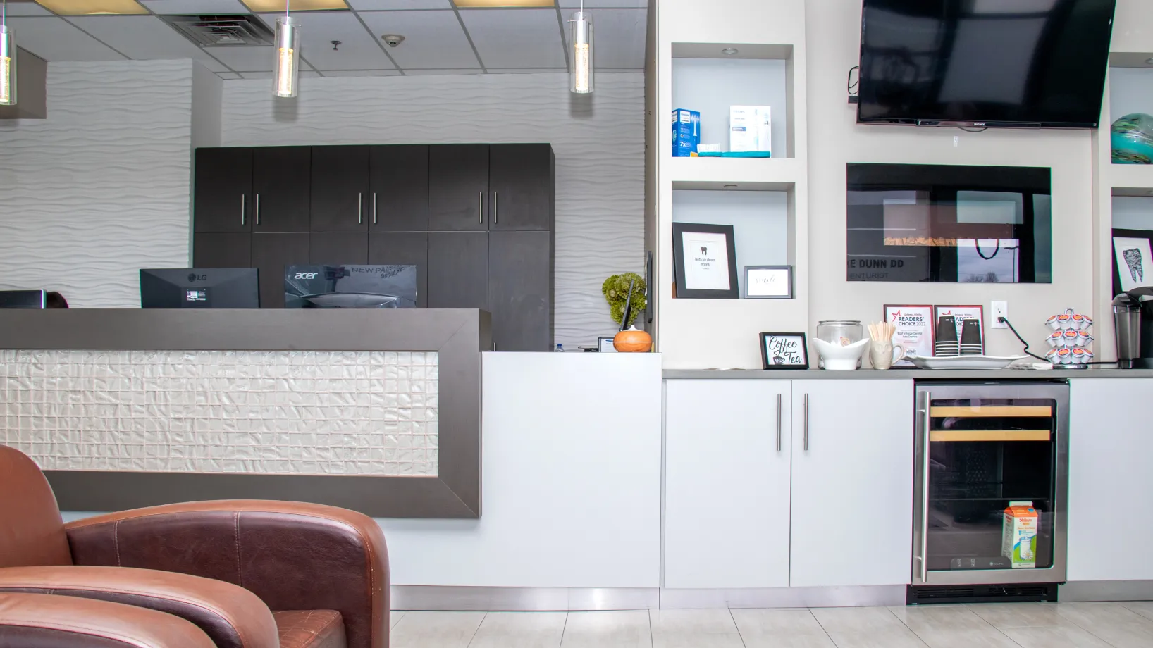 A modern reception area with a front desk, chairs, and a large wall-mounted TV.