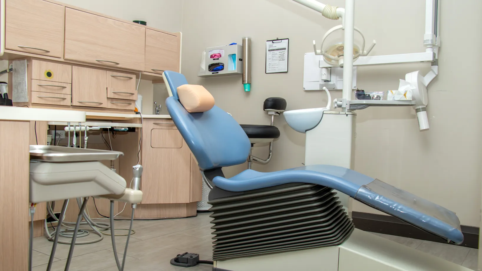 Dental office with an empty blue and gray chair and dental equipment ready for use.