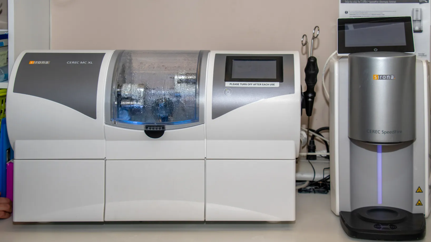 A dental milling machine and scanner on a counter, used for creating dental restorations.