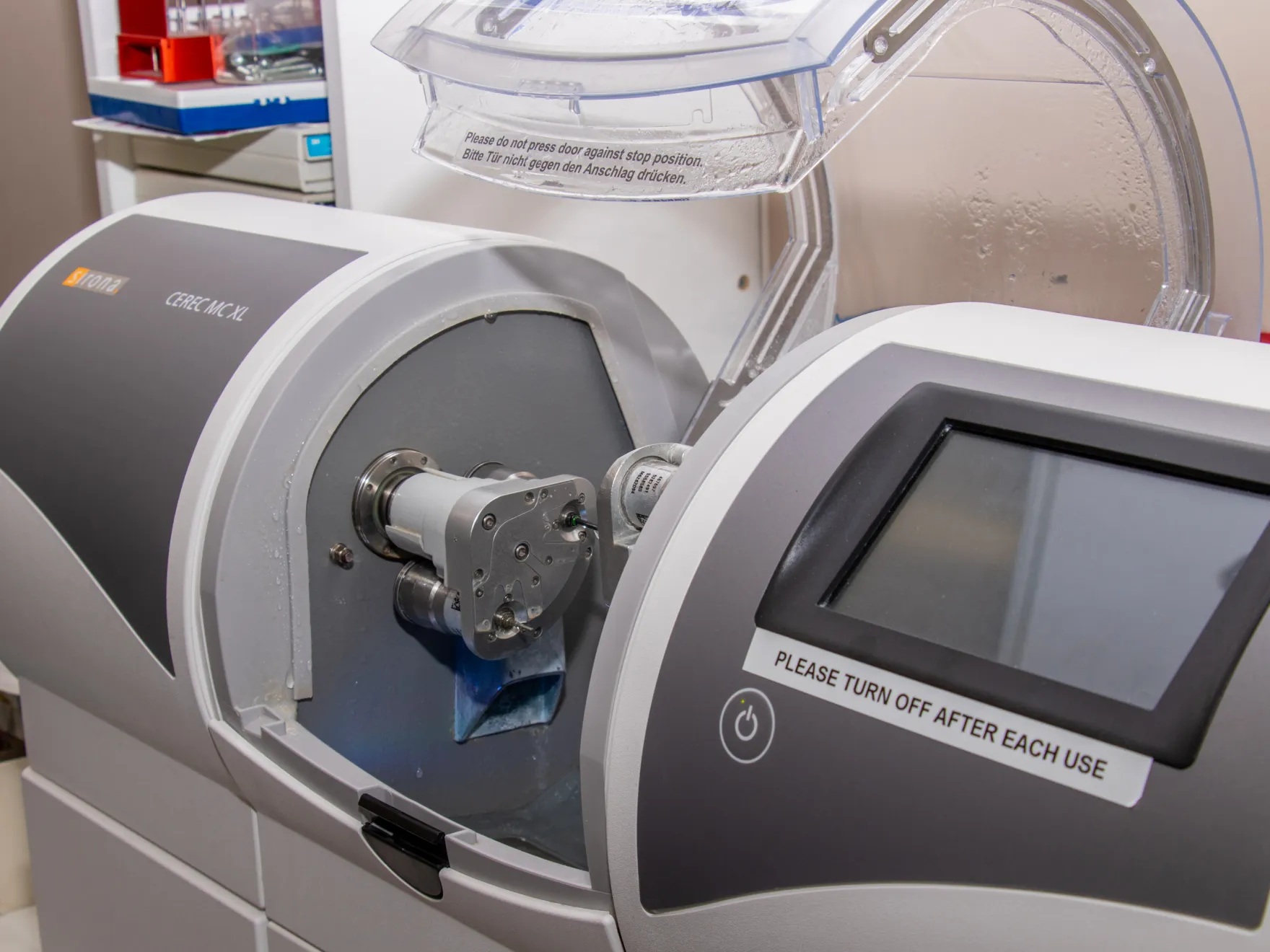 A dental milling machine with a partially open lid, used for creating dental restorations.