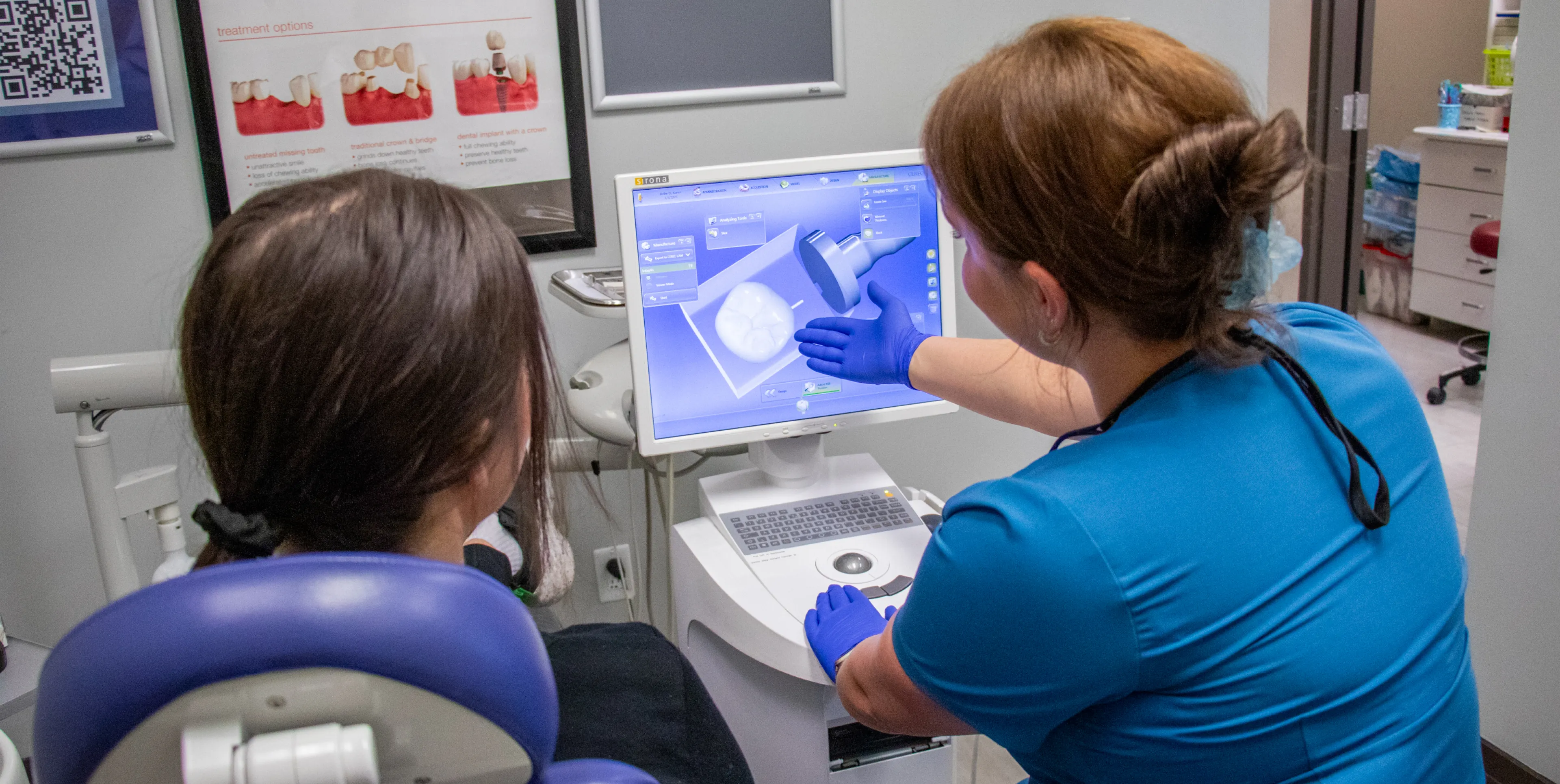 A dental professional shows a patient a scan on a monitor in a dental office.