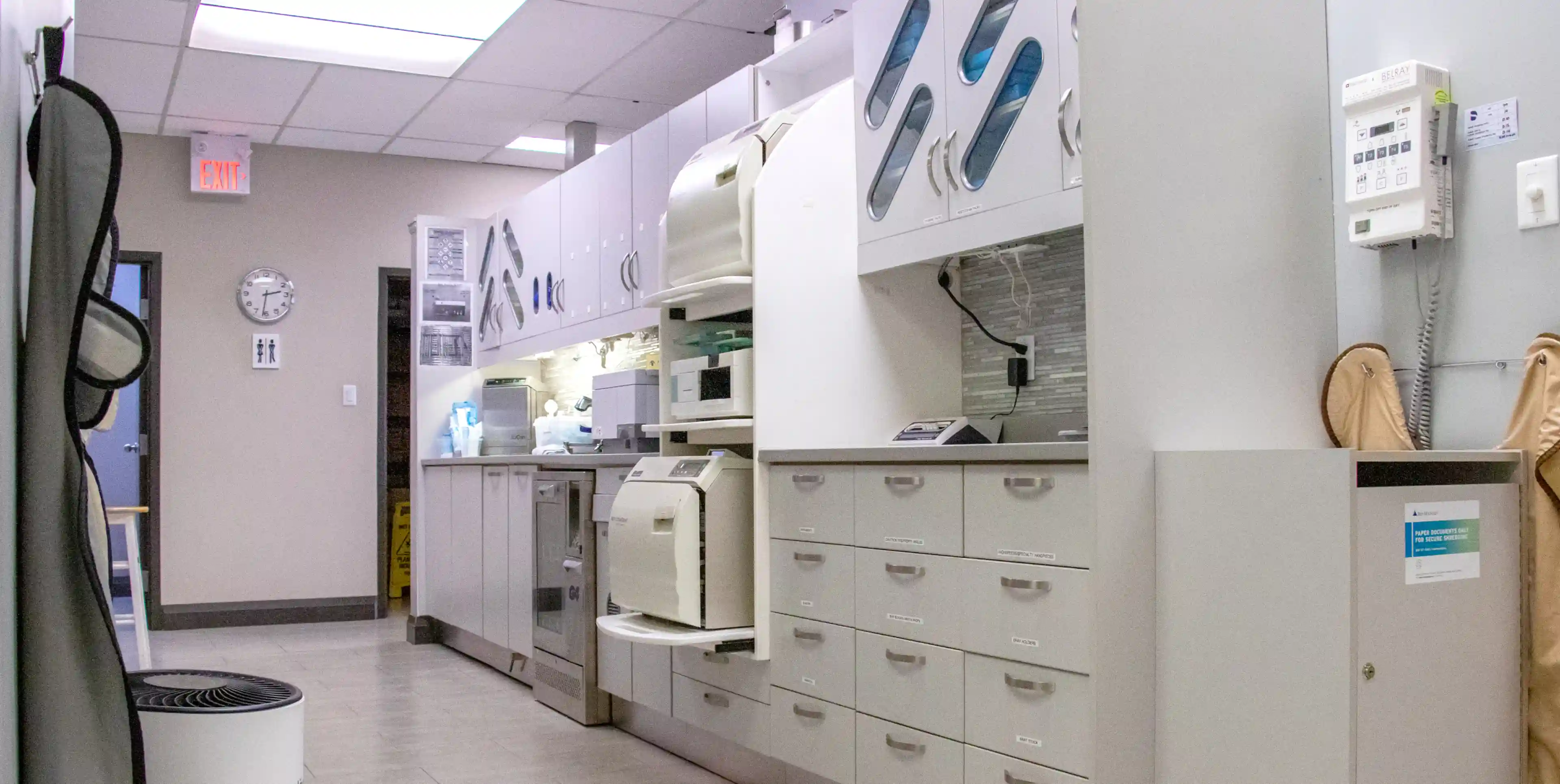 A modern dental office with white cabinets and sterilization equipment along the wall.