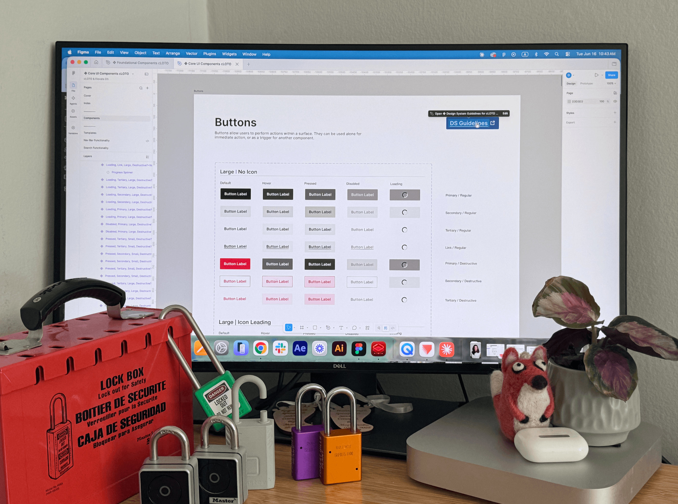 Desk with red lock box and several padlocks in front of a monitor showing button design guidelines.