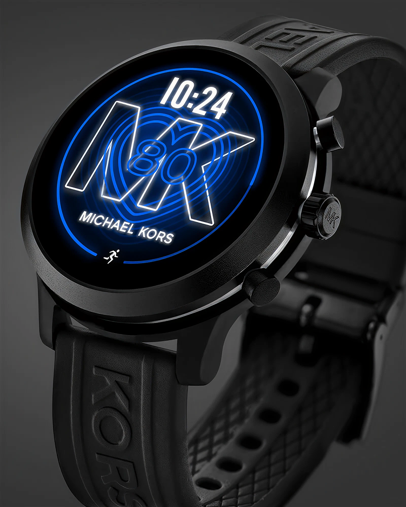 Close-up of a black Michael Kors smartwatch displaying time 10:24 with blue glowing MK logo.