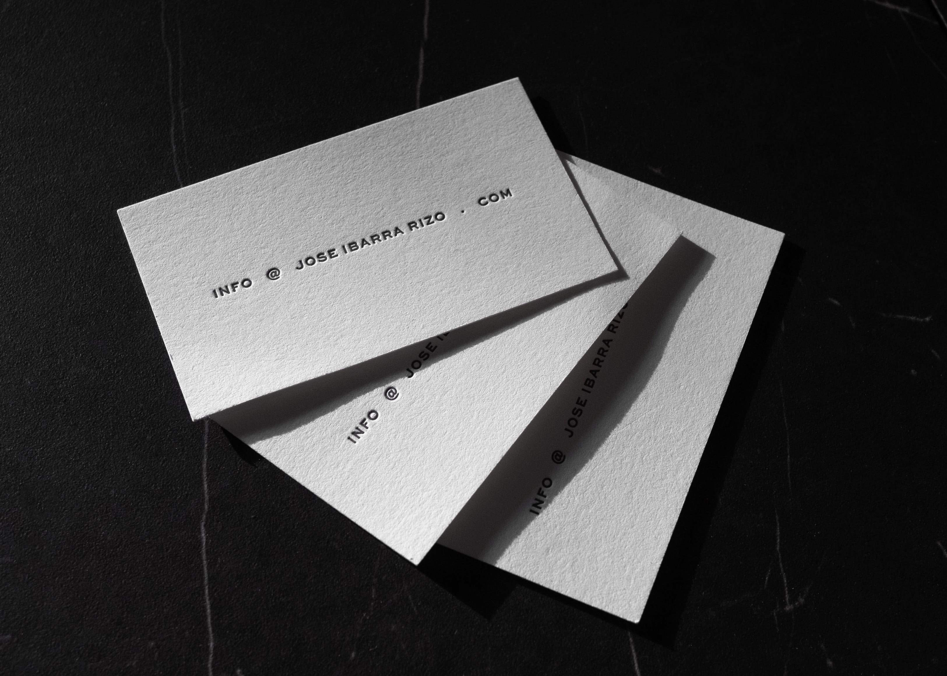 Two angled white business cards with text info @ joseibarrarizo.com on a black surface.