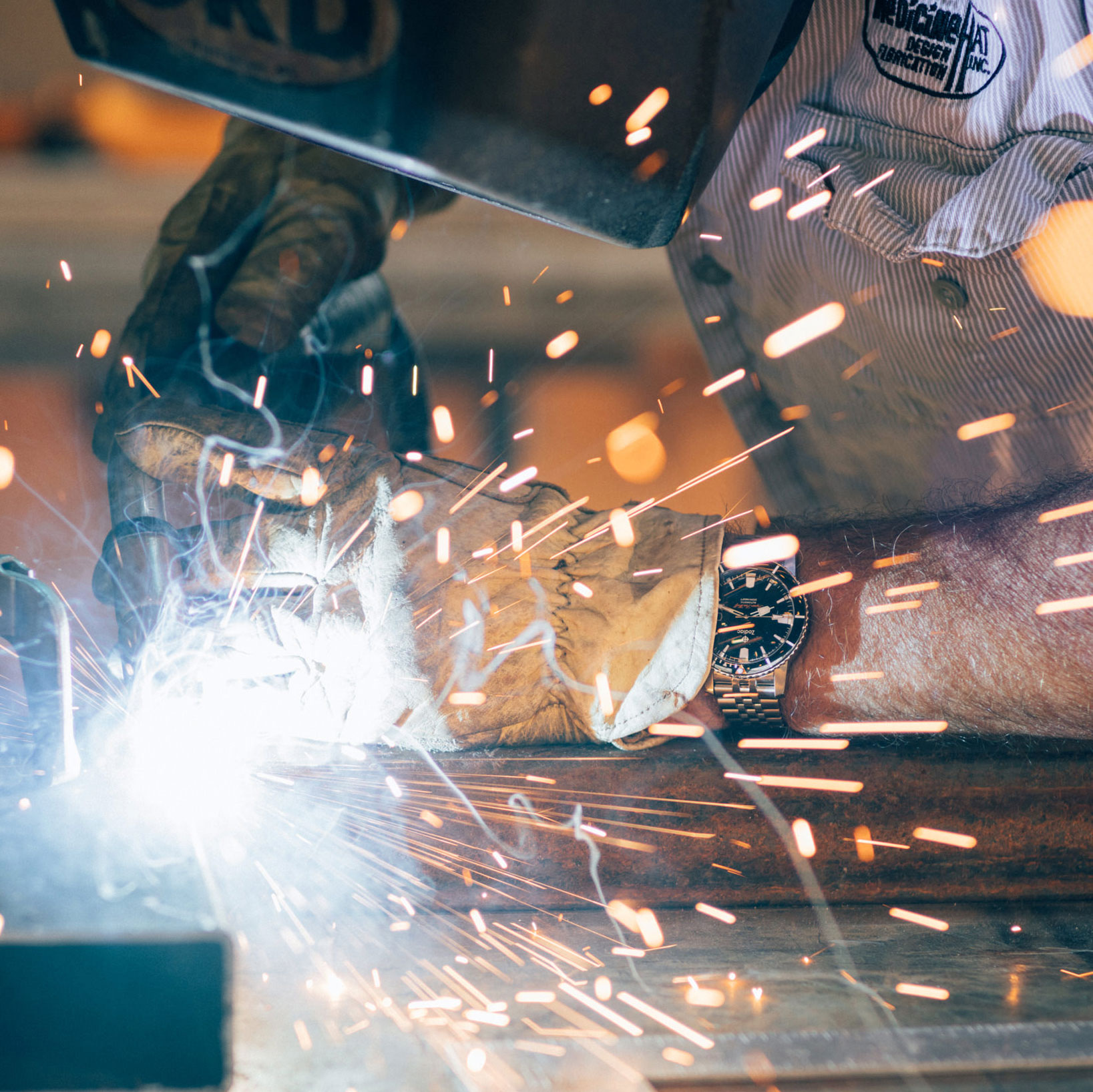 Close-up of a welder's gloved hands and sparks flying during welding work.
