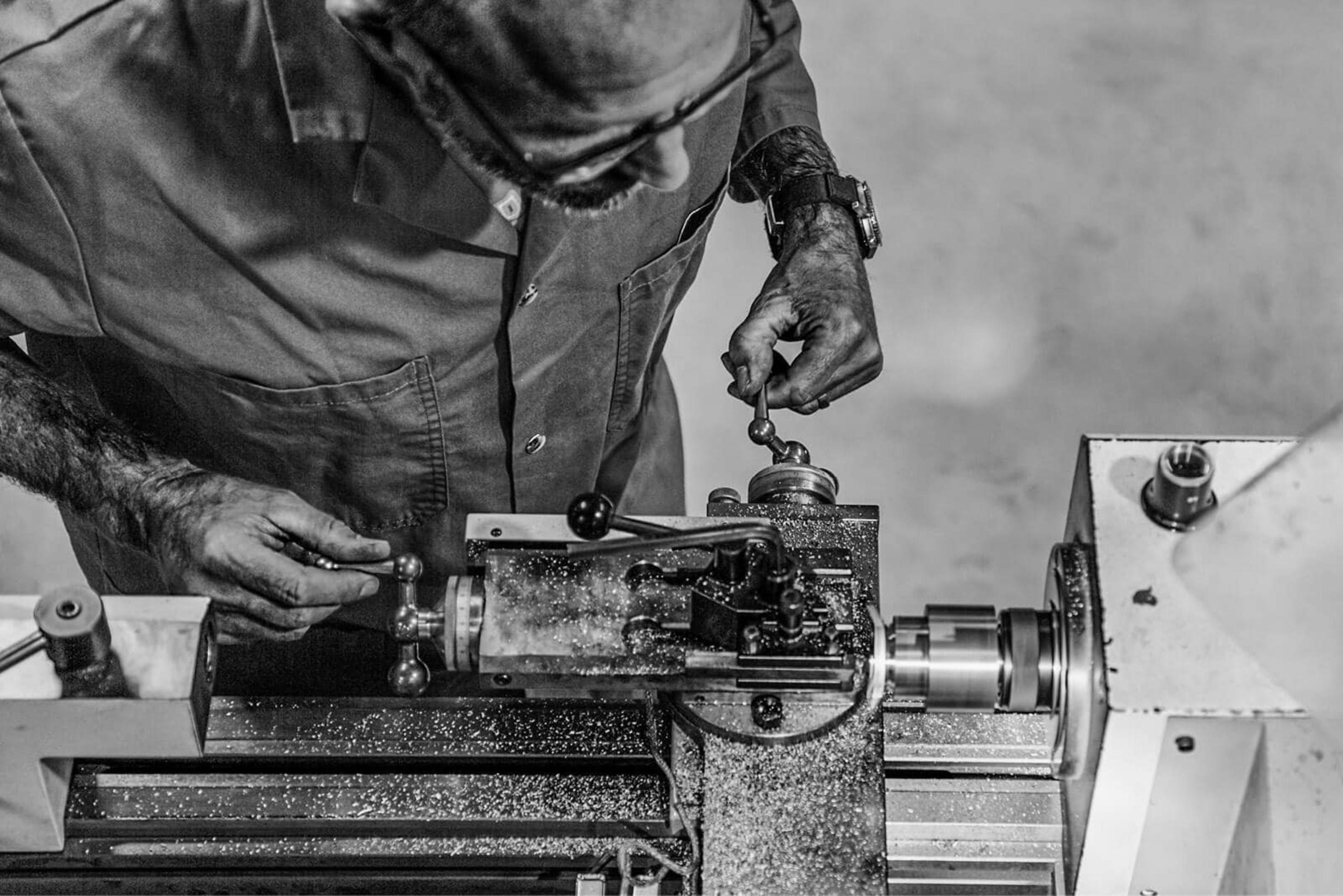 Man operating a metal lathe machine with metal shavings scattered around the tool.