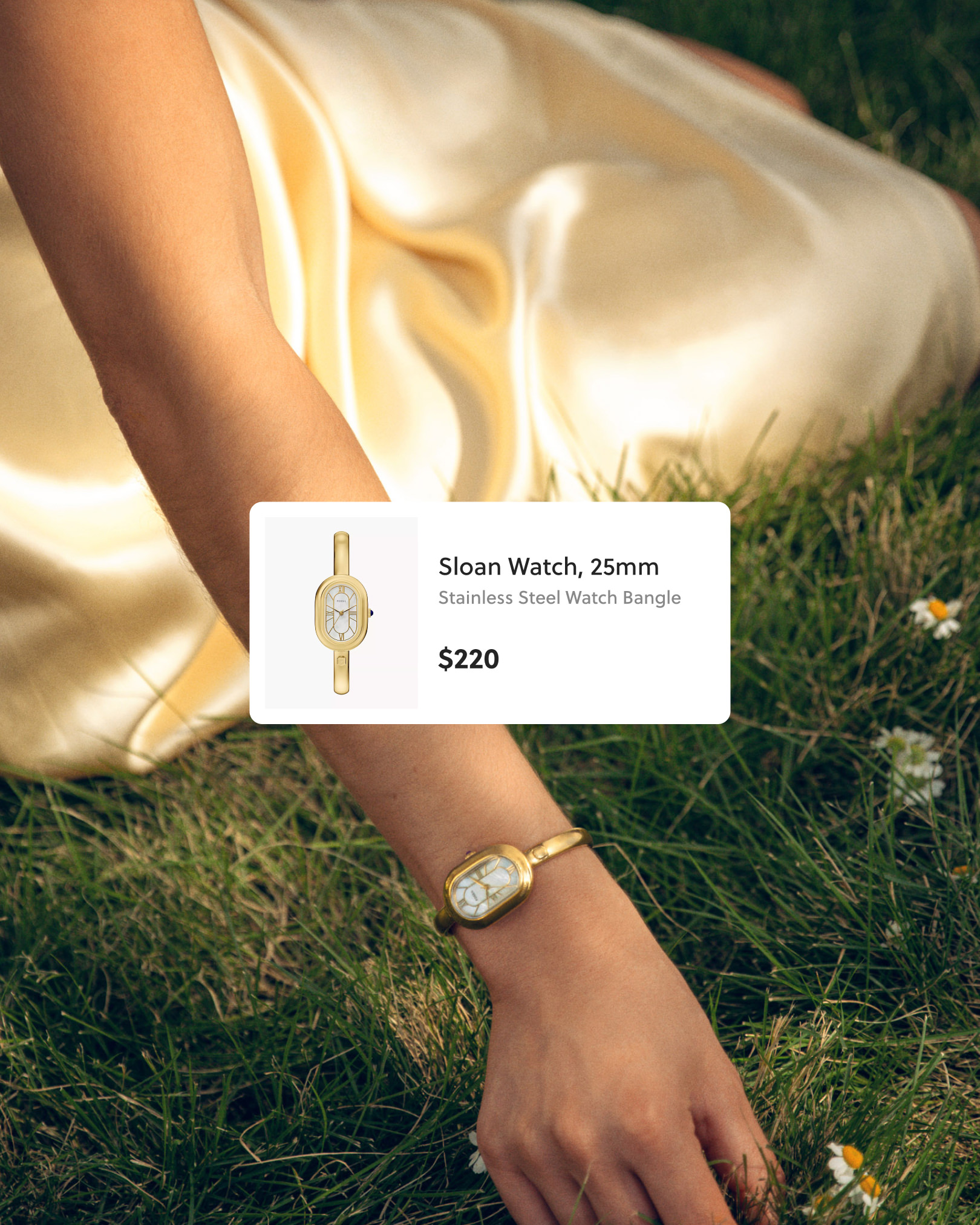 Arm resting on grass, wearing a gold Sloan 25mm stainless steel watch bangle.