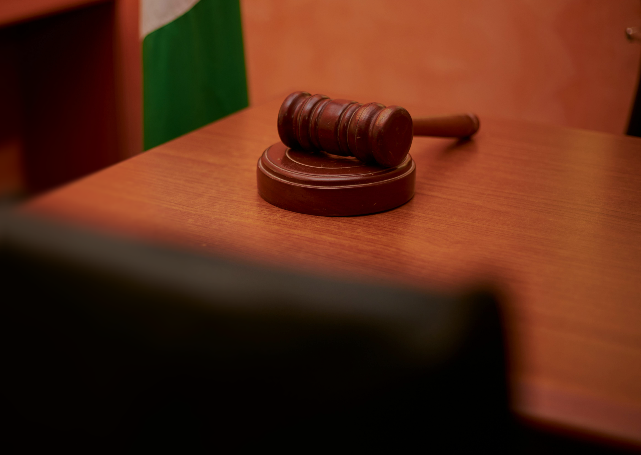 Wooden judge's gavel resting on a wooden desk with a blurred background.