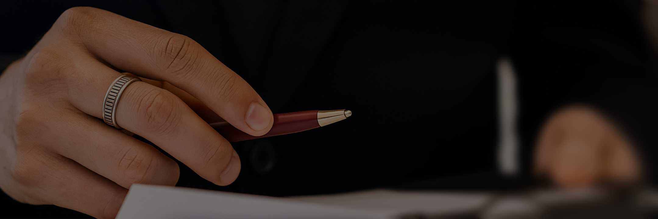 Close-up of a hand holding a pen poised to write on a paper.