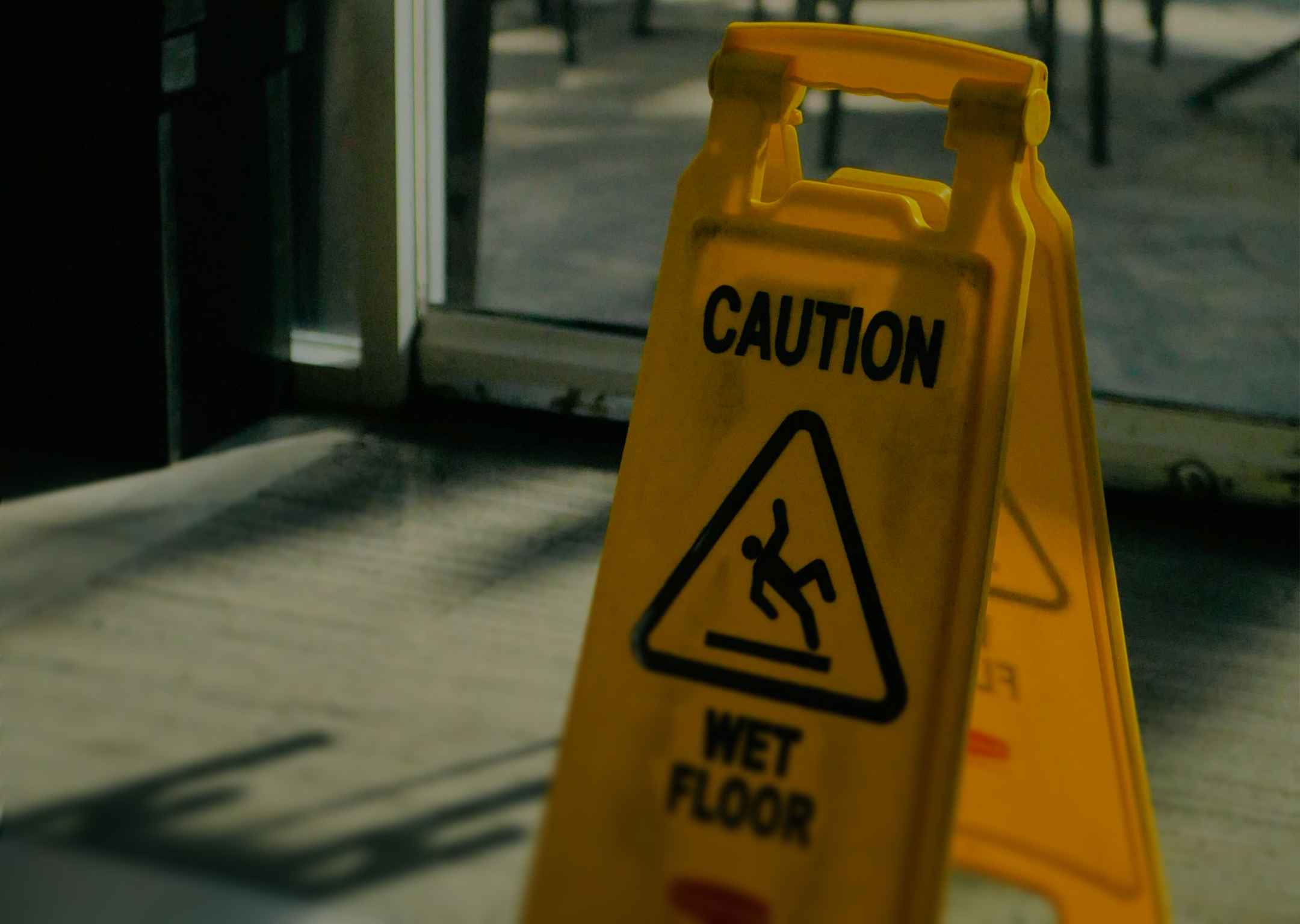 Yellow caution sign warning of a wet floor with a slipping figure symbol.