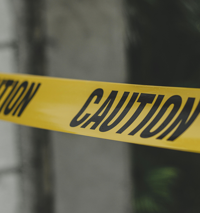 Close-up of yellow caution tape with black lettering stretched across an area.