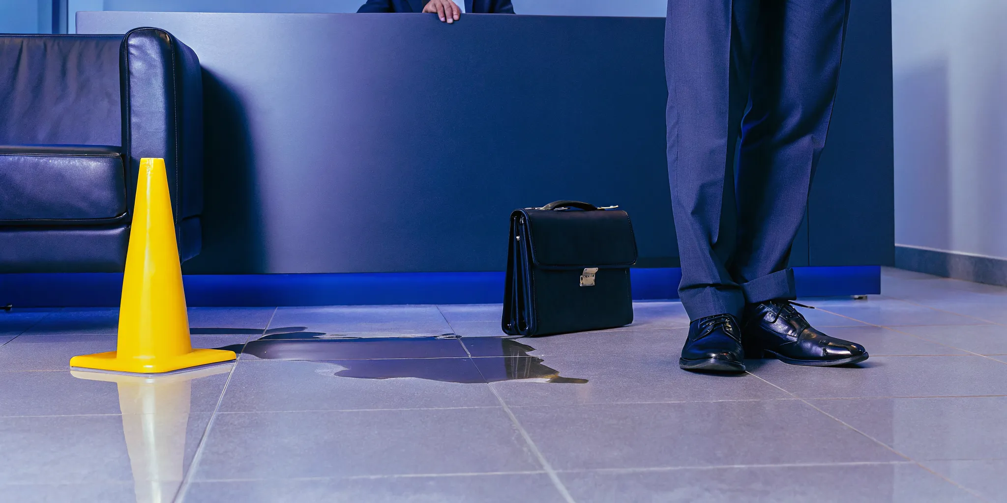 Man in a suit near a wet floor hazard, a common reason for suing for a slip and fall.
