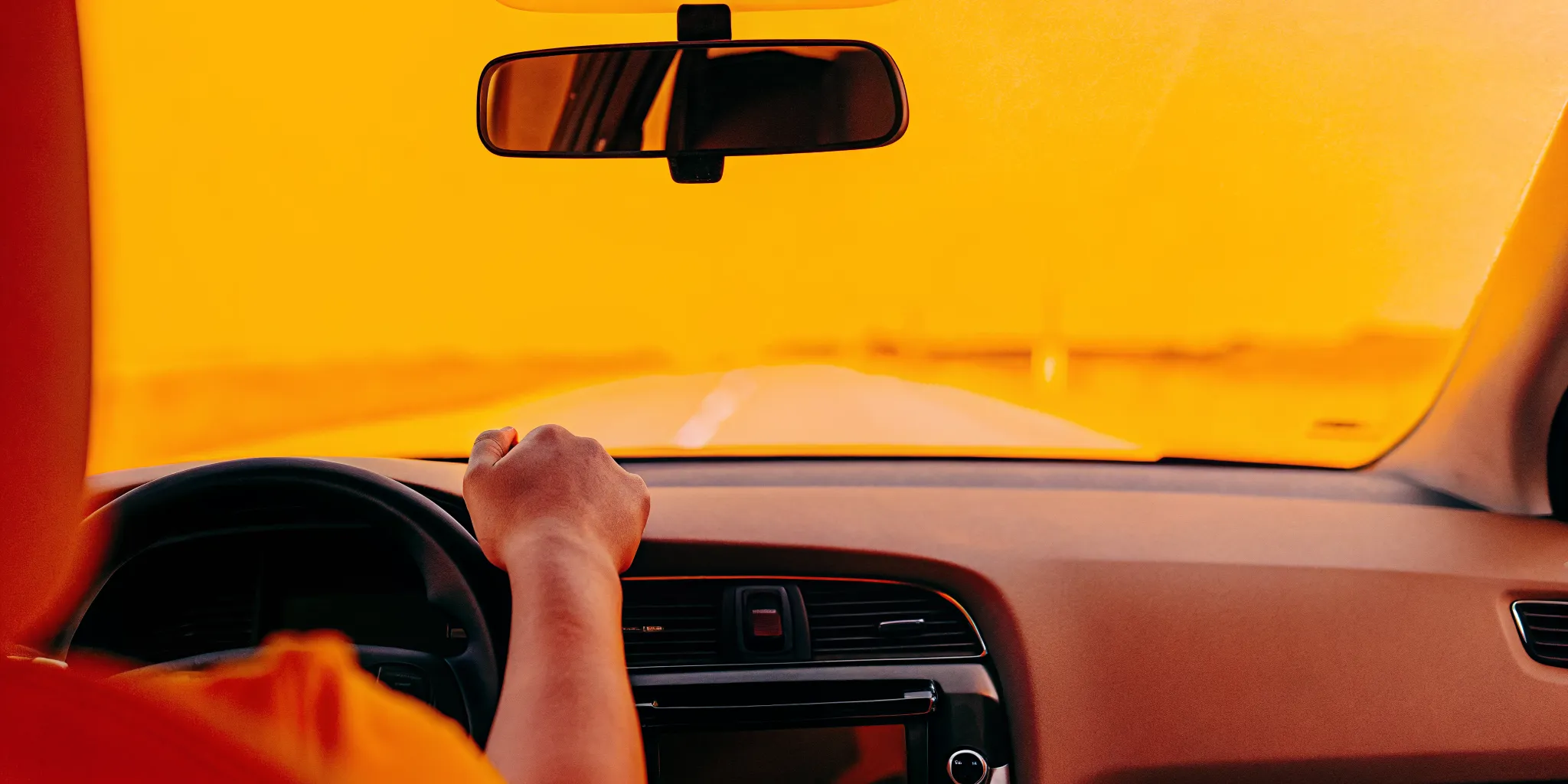 A driver reaching for a phone on the center console while driving on a Savannah street