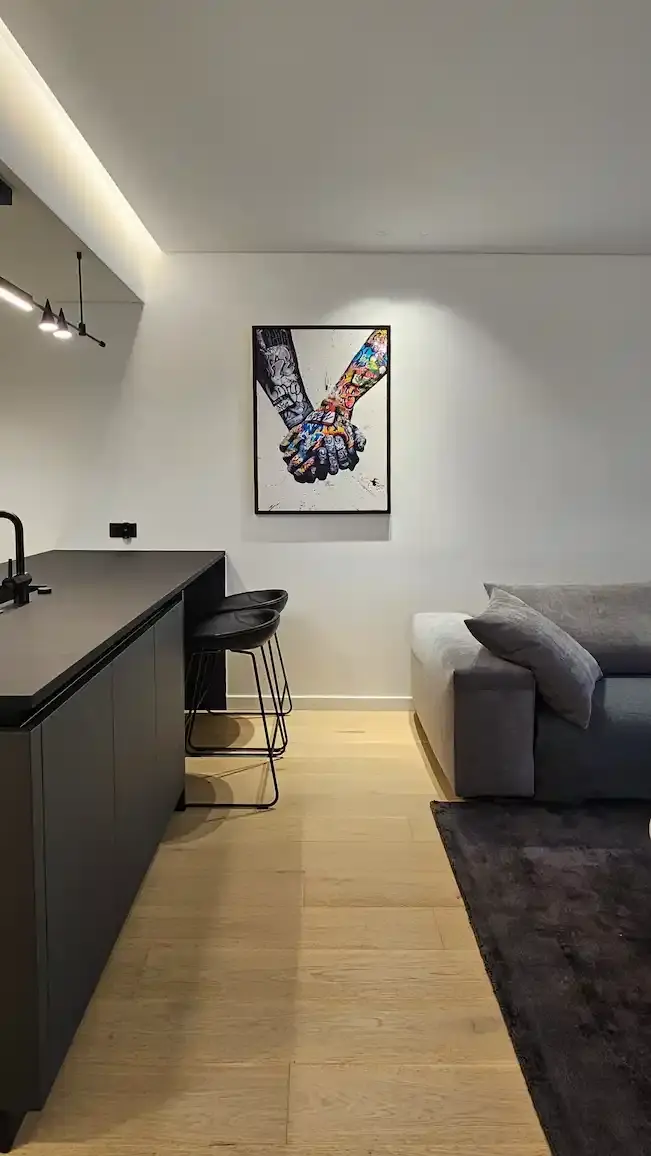 Minimalist living room with a cream sofa, round coffee table, ottoman, dining table with three white chairs, and modern circular ceiling lights.