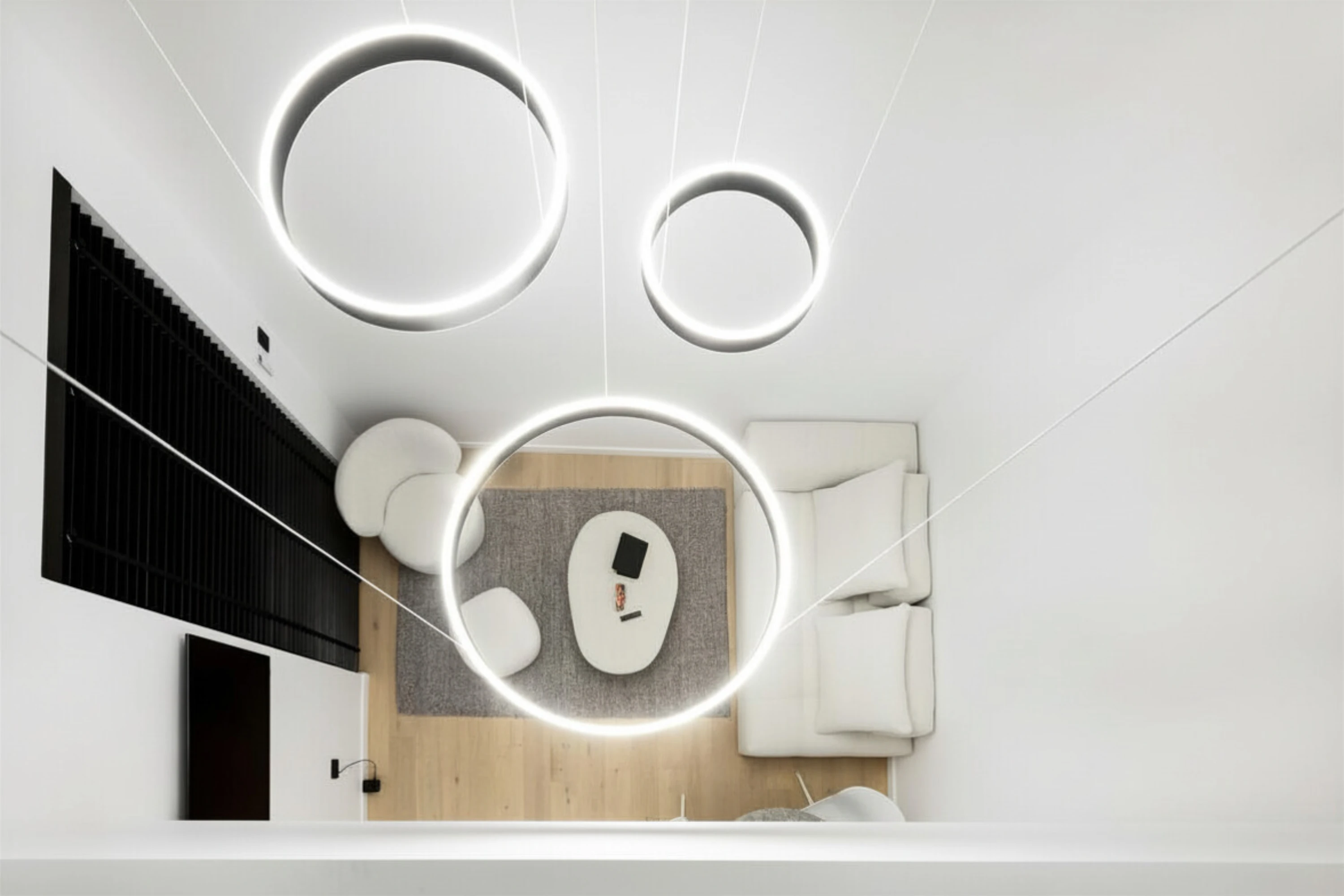 Modern bedroom with a large bed, gray throw blanket, wall-mounted TV, glass railing, and a study nook with shelves and a chair.