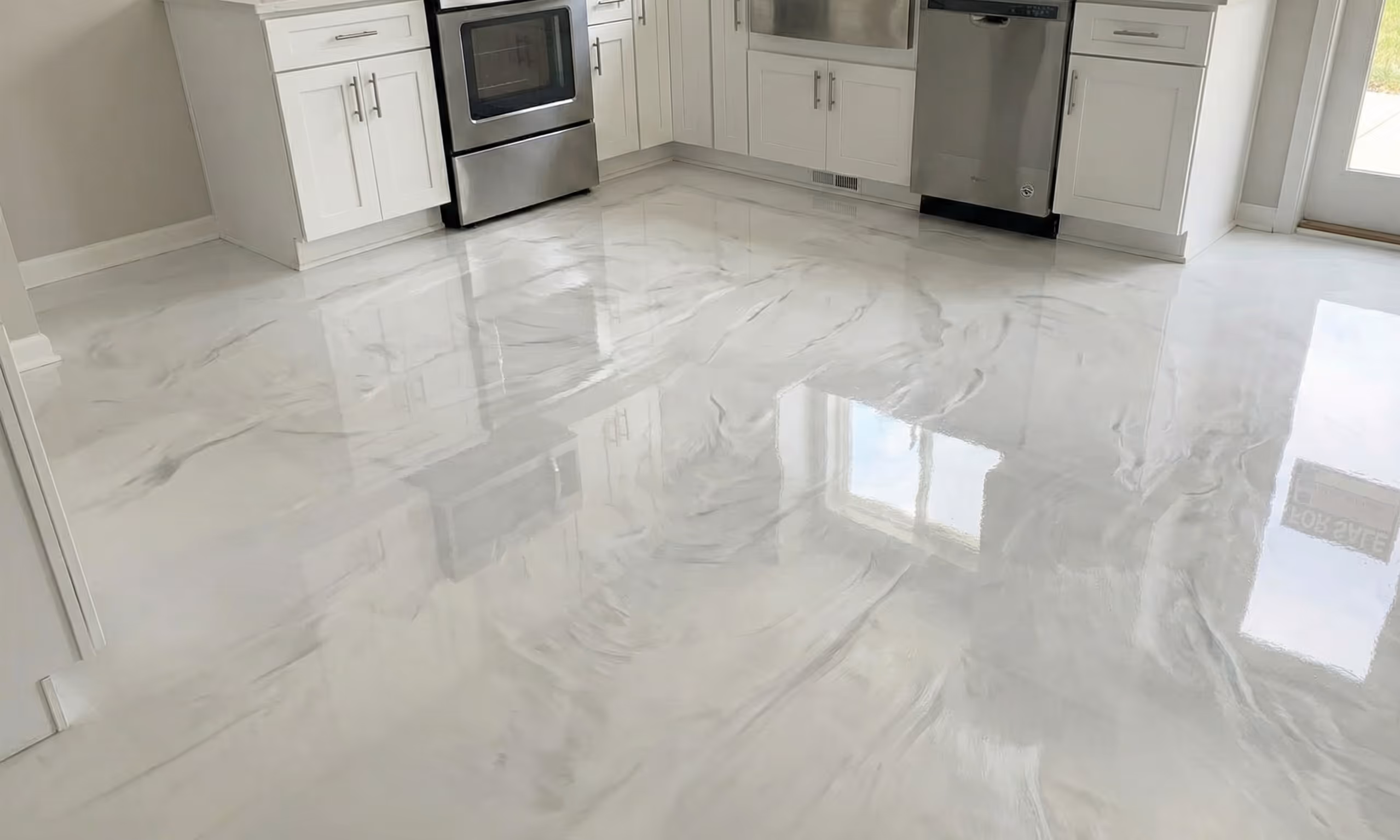 Modern kitchen with glossy white and gray marbled epoxy floor reflecting cabinets, stainless steel oven, dishwasher, and window.