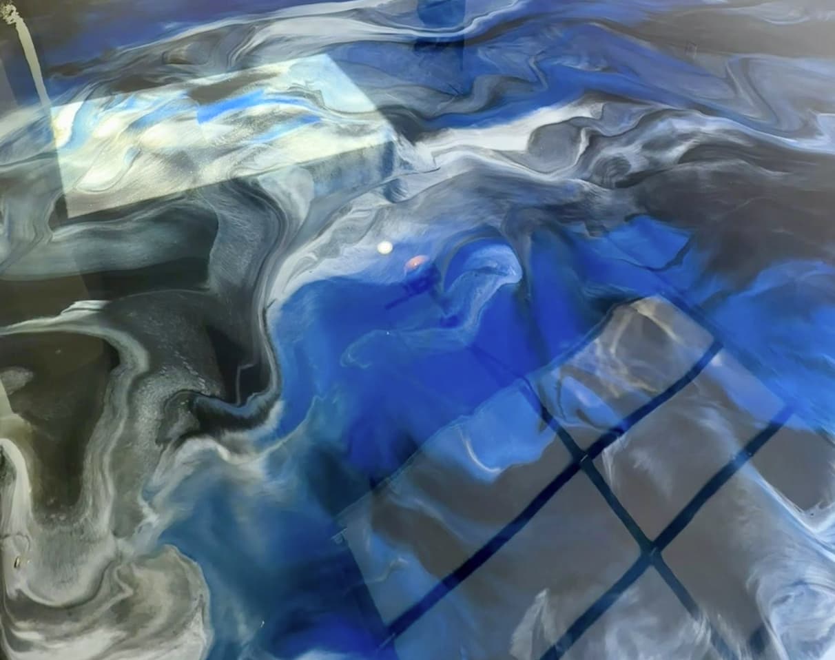 Swirling abstract patterns in shades of blue, gray, and black with reflections of a window grid.